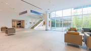 The entrance lobby and waiting area look out into an open-air atrium planted with trees and ferns.