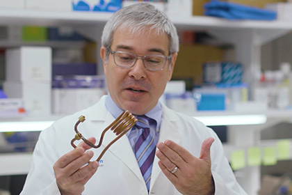 A man with gray hair examines a piece of curled copper tubing.