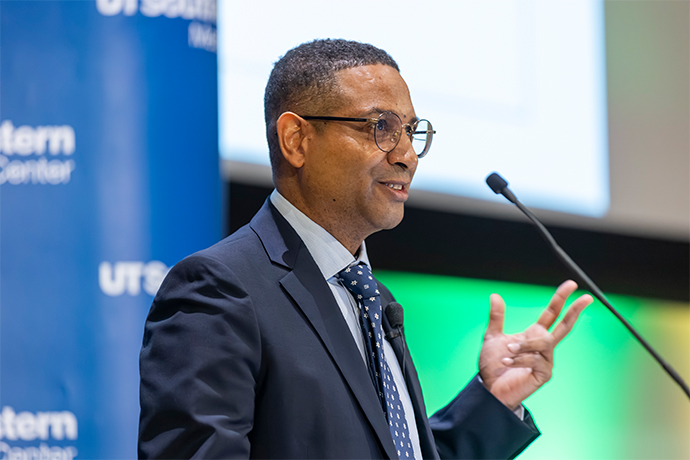 Well-dressed man speaks into a microphone.