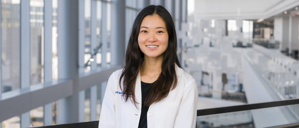 woman in white lab coat, black shirt, long black hair