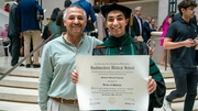 Mahmoud Elguindy, a Perot Family Scholar, shows off his medical degree officially making him an M.D./Ph.D., alongside his father.