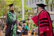 Dr. Robert Hermann receives his degree from Dr. Podolsky.