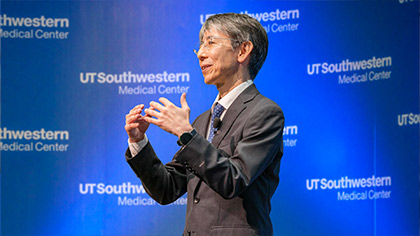 Man in suit speaking in front of UTSW background