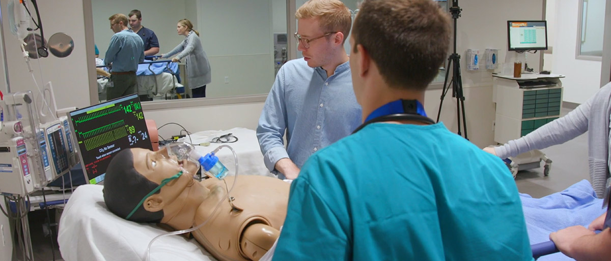 Three people in a room with a dummy