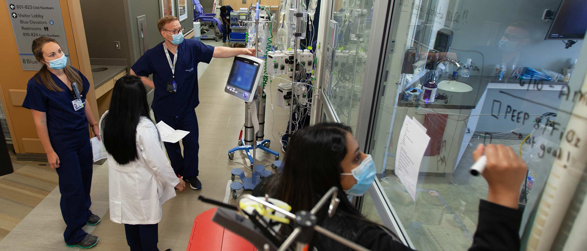 Two people in lab coats looking at tray of gel