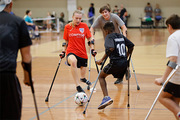 Amputee wheelchair soccer players jockey for control of the ball.
