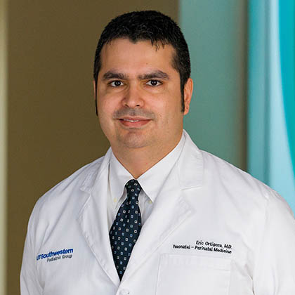 Man with dark hair, black tie, white lab coat