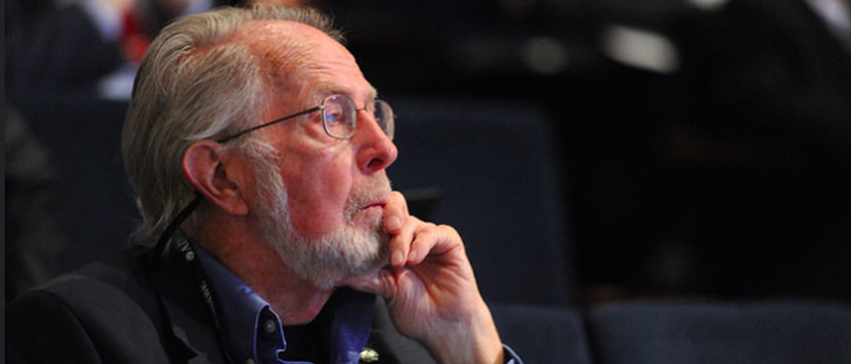 bearded man wearing suit sitting in auditorium