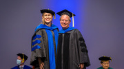 Samantha Johnson poses for a photo with her mentor, David Corey, Ph.D., Professor of Pharmacology and Biochemistry, after being hooded.