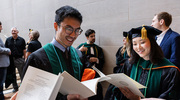 James Ye, M.D., Ph.D., left, and Gina Park, M.D., Ph.D., look for their names in the commencement program before the ceremony begins.