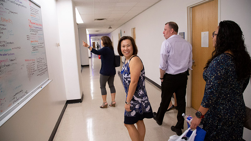 Four people walking down hallway, one is looking back and smiling