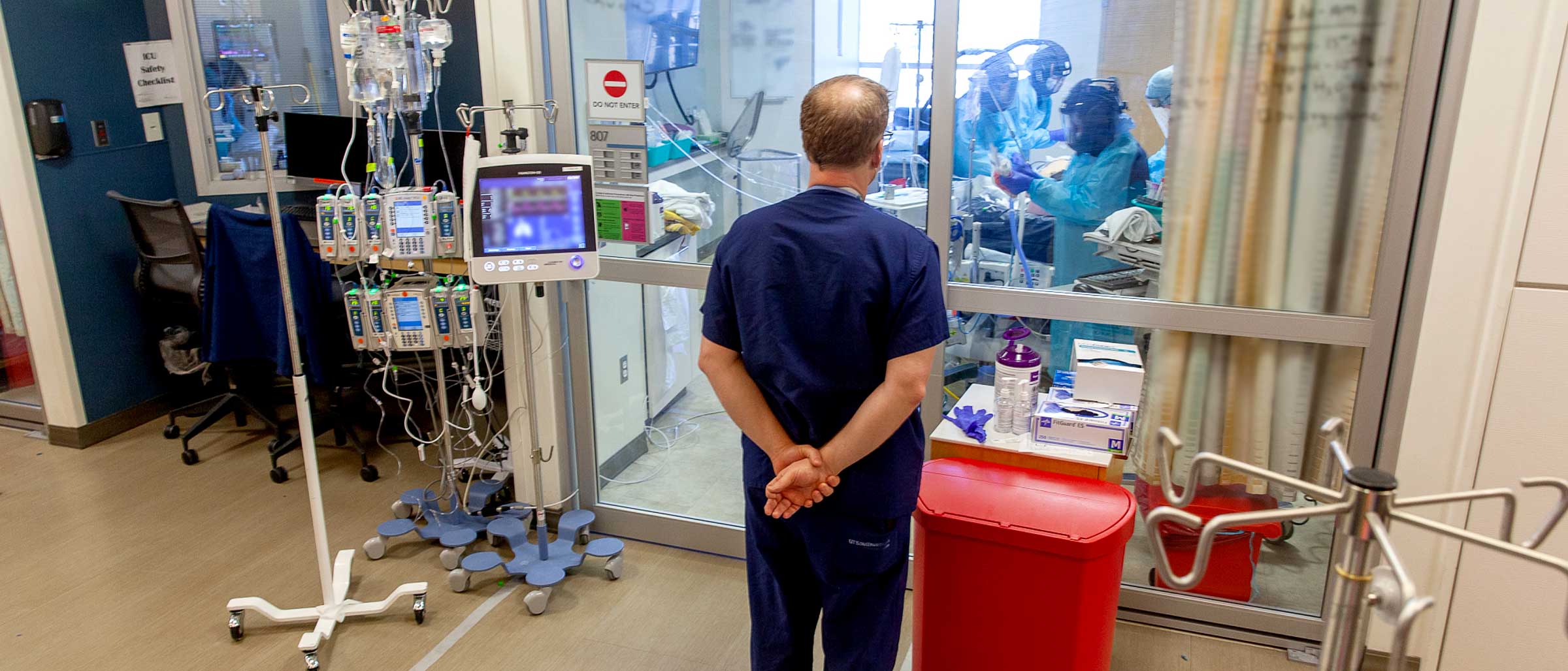 Woman using IR thermometer on man's head, both wearing masks