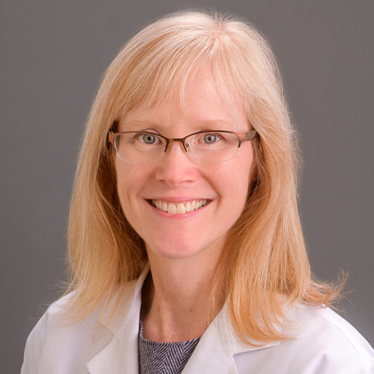 Woman with blonde hair wearing glasses and a lab coat