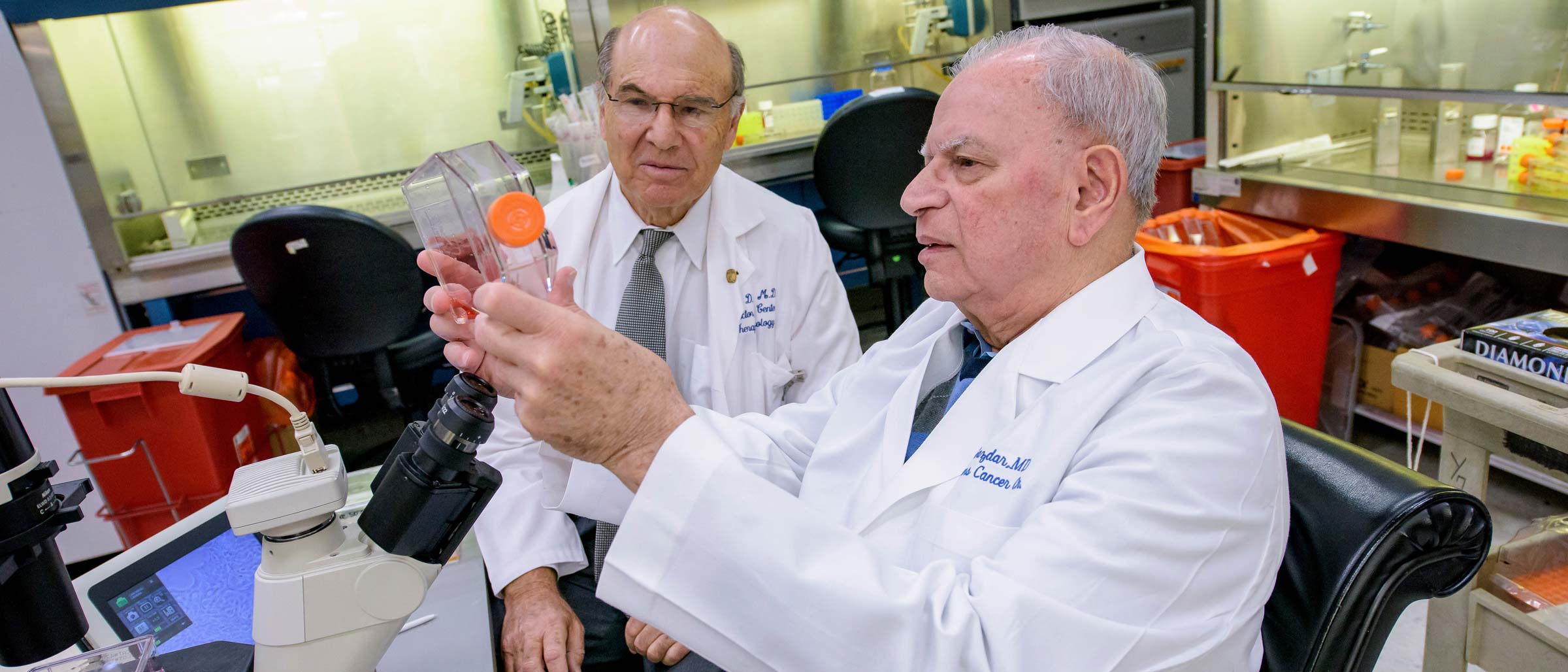 Two men in white lab coats looking at a bottle