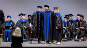 Don Gammon, Ph.D., Associate Professor of Microbiology, left, and Neal Alto, Ph.D., Professor of Microbiology, right, pose with Molecular Microbiology graduate Aaron Embry, Ph.D., after he is hooded.