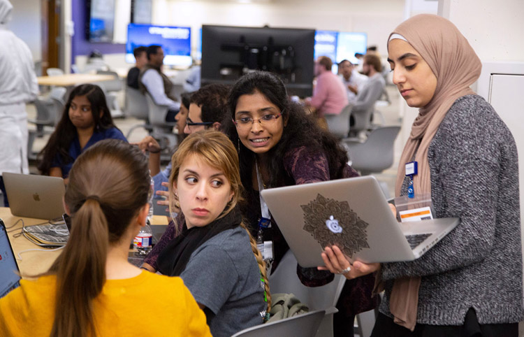 A group of four women looking at one's laptop and discussing