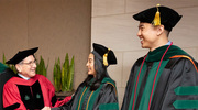 Graduates shake hands with UTSW President Daniel K. Podolsky, M.D., (left) as they receive their diplomas.