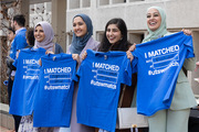 A group of female medical students celebrates their matches together, Match Day shirts in hand.