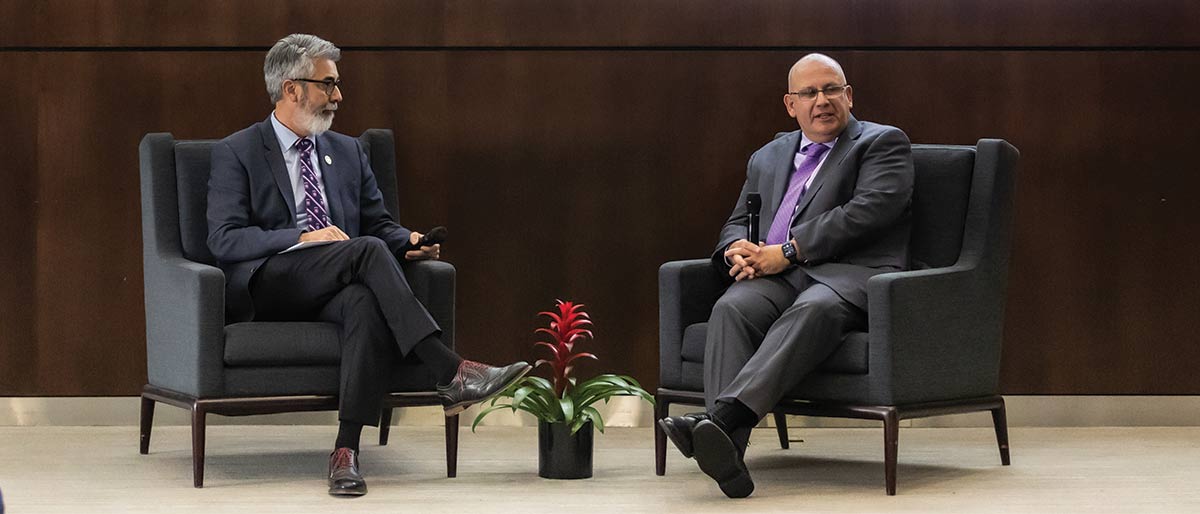 two men sitting in chairs on the stage