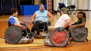 Four participants gather to play wheelchair rugby.