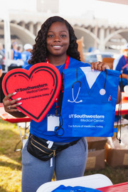 Kerinthia Hamilton, whose mother Marion Hamilton works with UTSW, pitched in at the UT Southwestern booth showing some of the swag participants picked up.