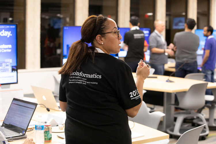 Woman with glasses, ponytail, wearing a bioinformatics shirt