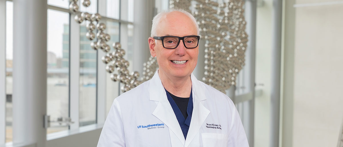 Man with gray hair, glasses, wearing white lab coat