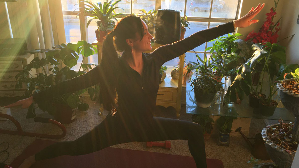 Woman doing yoga in room surrounded by plants