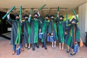 A group of students celebrate receiving their diplomas.