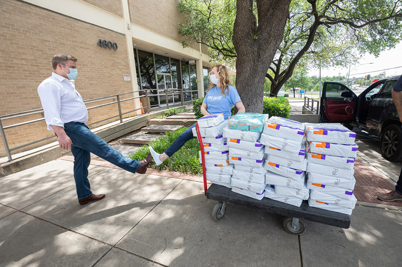 Man and woman in masks standing by cart of boxes