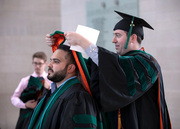 Dr. Alvand Seahat (left) and Dr. Evan Barrios (right) help one another with regalia.