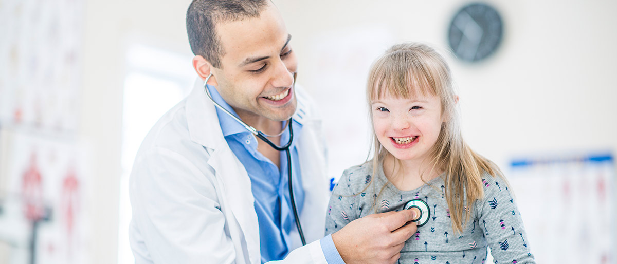 Child with down syndrome receiving exam from doctor