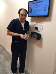Weihan Lee, Radiation Oncology, poses by the clock where staff clock in.