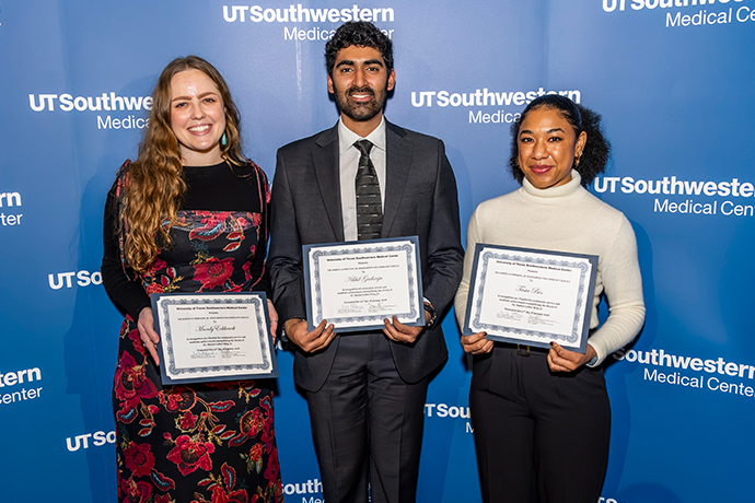 Three smiling people holding award certificates.