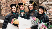Doctor of Physical Therapy graduates, holding flowers, proudly show off their new diplomas in a group photo.