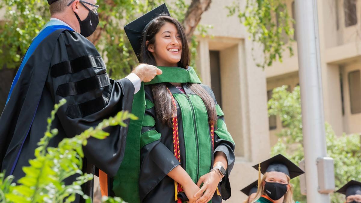 Woman in black graduation gown receiving green stoll