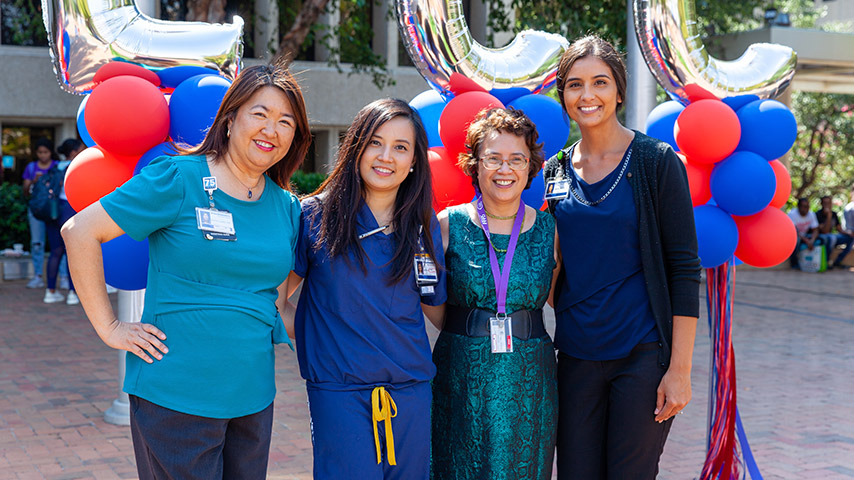 Four female UTSW employees standing in front of balloons