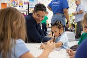 Roberto Gonzalez, M.D., Principal at Biomedical Preparatory, observes a group of students working diligently on their alphabet writing skills.