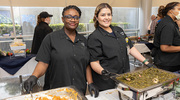 Nutrition Services team members Oluwatoyin Dunn (left) and Lorena Perez serve up sweet potatoes and collard greens.