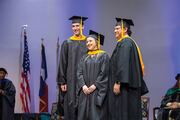 Prosthetics and Orthotics graduate Hali Crellin (center) poses for a photo on the stage with Drs. David G. Wilson (left) and Miguel N. Mojica, Assistant Professors in the School of Health Professions.
