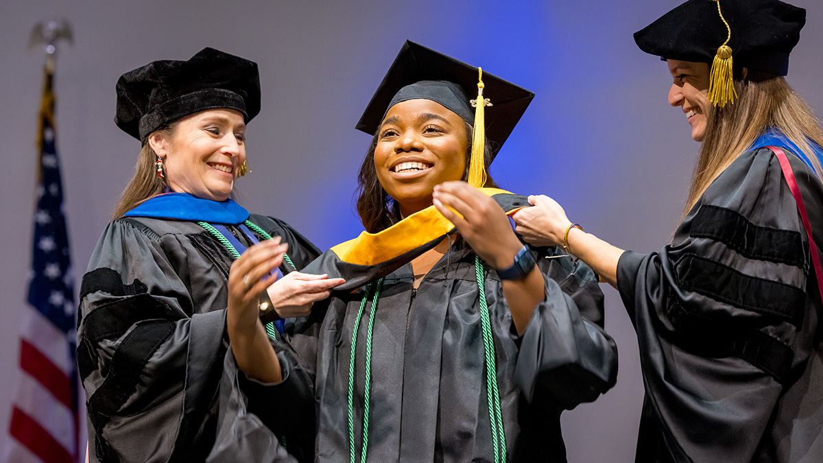 Master of Clinical Nutrition graduate Laci Baker is hooded by Clinical Nutrition faculty members Lona Sandon, Ph.D., (left) and Anne Gilmore, Ph.D.