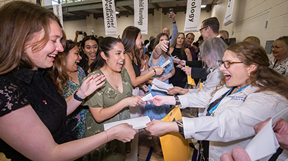 Excited students being handed an envelope.