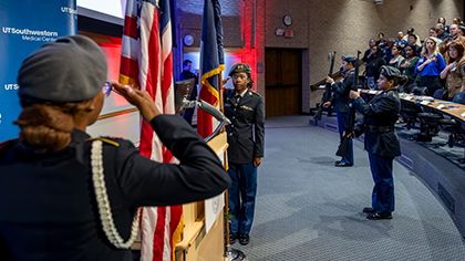 ROTC rifle corps salute the flags on stage during event
