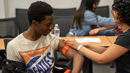 Two students practice using a tourniqut.