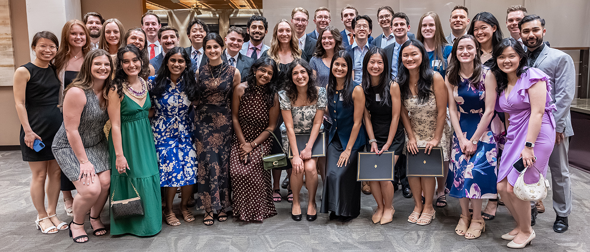 A large group of well dressed men and women pose together.