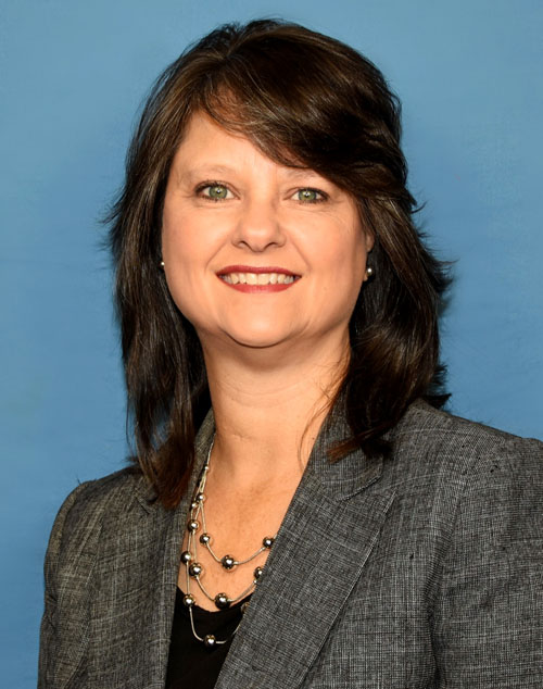 Woman with shoulder length dark hair and a dark grey jacket.