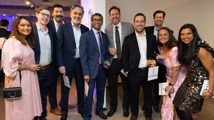group of smiling diverse people at gala surrounding Dr. Gurram in the center in blue suit with trophy