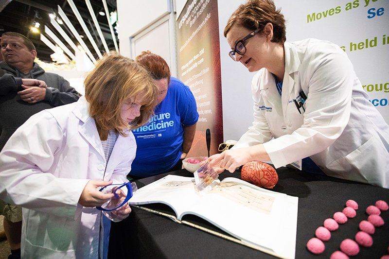 Amy Zwierzchowski-Zarate, a student in the Neuroscience Ph.D. Program, shares a display of animal brains with budding scientists at the Ask a Brain Scientist station.