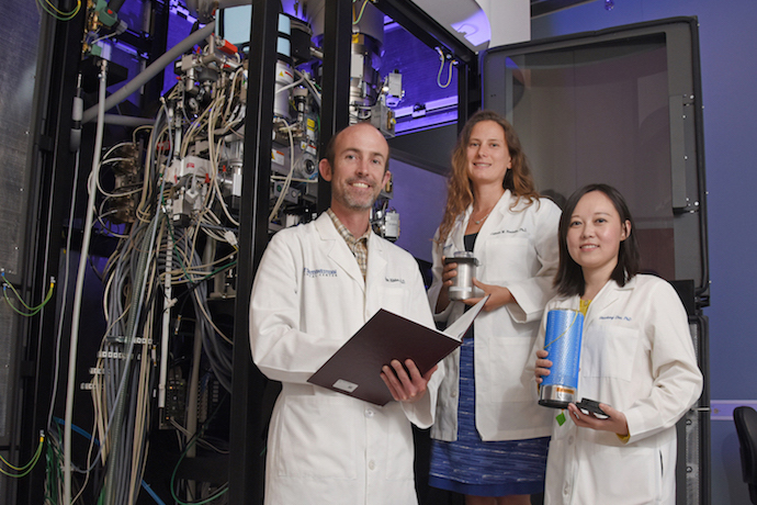 Three researchers in front of machine
