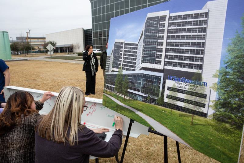 UTSW Employees signing support beam in front of tower and rendering